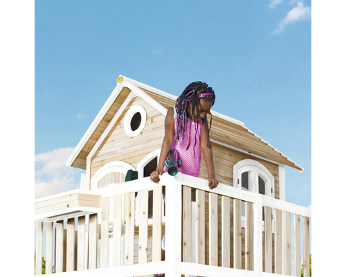 Mädchen auf einem Spielturm mit Holzhaus im Garten