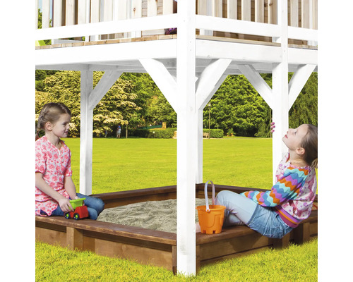 Spielturm mit Sandkasten und spielenden Kindern im Garten.