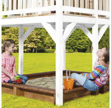 Zwei Kinder spielen in einem Sandkasten mit Überdachung in einem Garten.