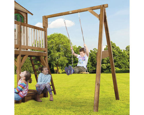 Kinder spielen auf einem Holzspielturm mit Schaukel im Garten.