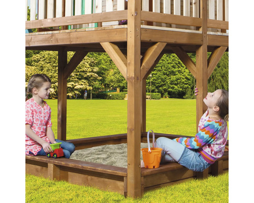Spielturm mit Sandkasten und zwei spielenden Kindern im Garten.