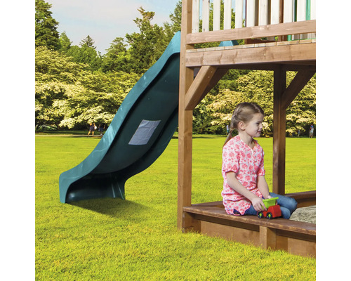 Spielplatz mit Rutsche und spielendem Kind im Sandkasten