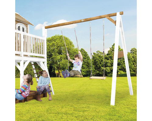 Kinder spielen auf einem Holzspielplatz mit Schaukeln im Garten.