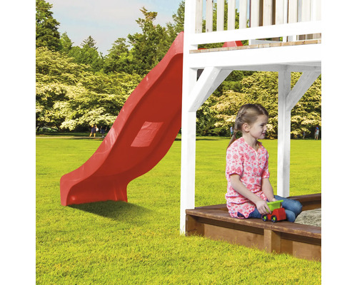 Spielplatz mit roter Rutsche und Mädchen im Sandkasten