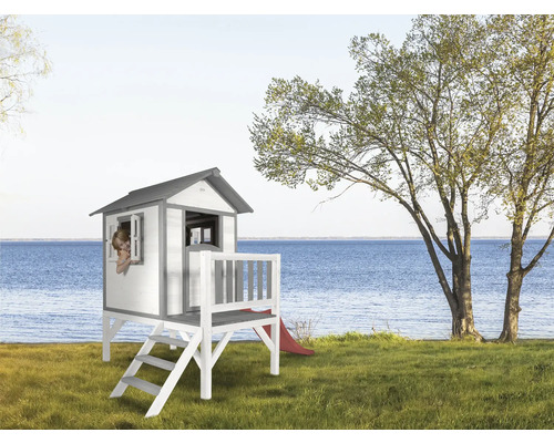 Holzspielhaus mit Treppe und Rutsche im Garten mit Blick auf den See