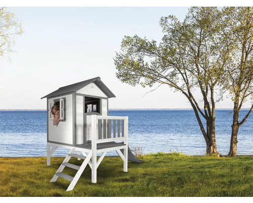Spielhaus aus Holz mit Rutsche auf Rasenfläche am See