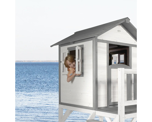 Spielhaus am Strand mit Kind am Fenster.