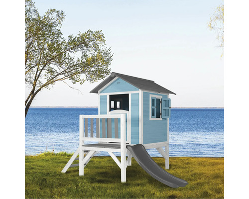 Spielhaus aus Holz mit Rutsche und Fensterläden vor dem Hintergrund eines Sees