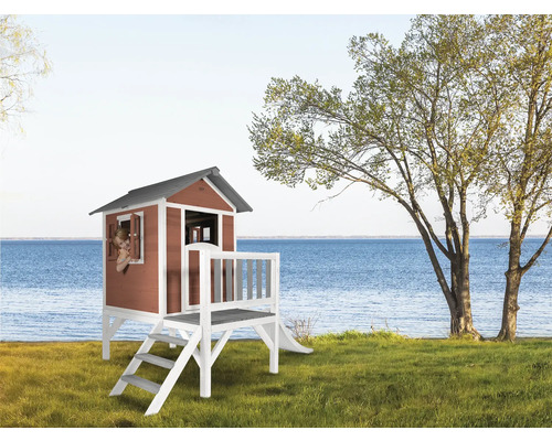 Spielhaus aus Holz mit Rutsche und Terrasse im Garten mit Blick auf den See.