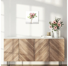 Wandbild mit Blumenarrangement über einem Holzschrank