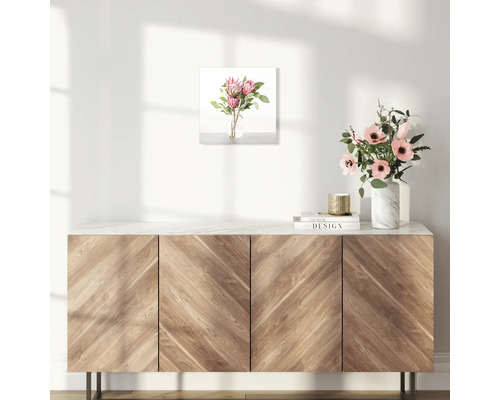 Wandbild mit Blumenarrangement über einem Holzschrank