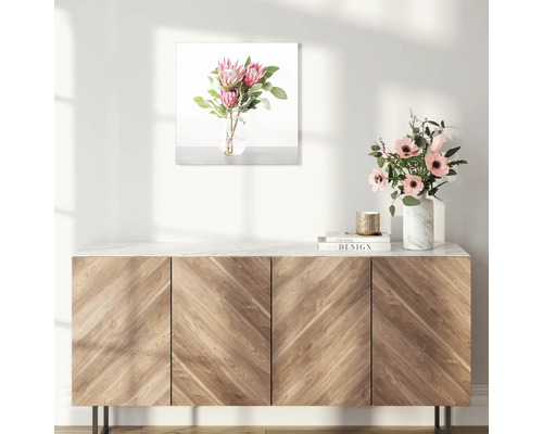 Dekoratives Bild mit Blumenarrangement über einem Holzschrank.