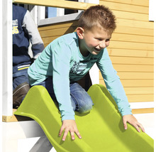 Kind rutscht auf einer Rutsche eines Spielhauses herunter.