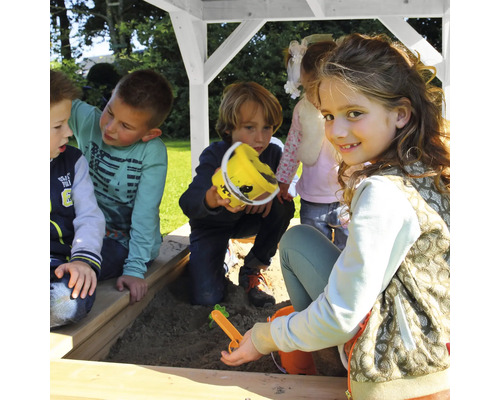 Kinder spielen in einem Sandkasten mit Holzrahmen.
