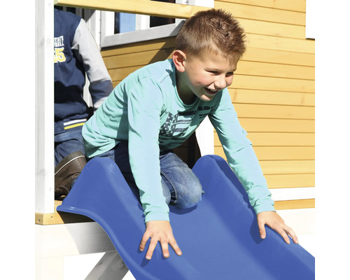 Ein Junge rutscht eine blaue Rutsche in einem Spielhaus hinunter.
