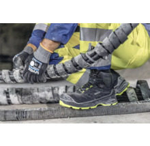 Arbeiter mit Uvex Sicherheitsstiefeln und Uvex Arbeitshandschuhen bearbeitet ein Bauteil.