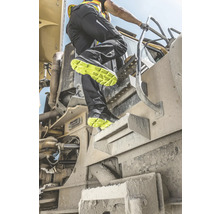 Ein Mann steigt mit Arbeitsschuhen auf eine Baumaschine.
