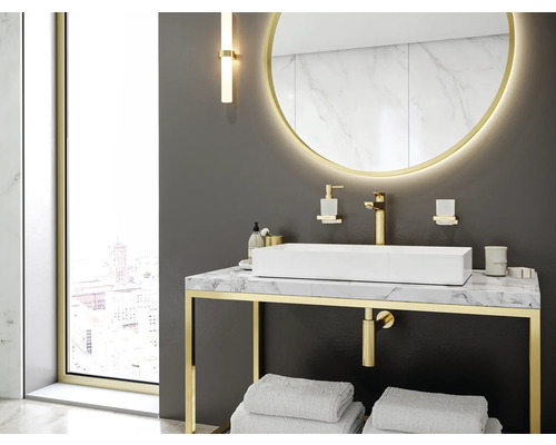 Modernes Badezimmer mit rechteckigem Waschbecken auf Marmorplatte, goldenen Armaturen und rundem Spiegel mit Beleuchtung