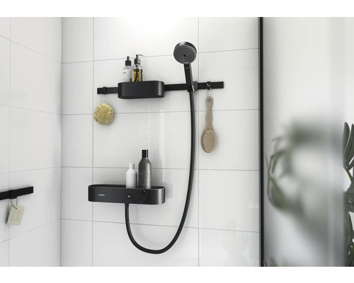 Badezimmer mit Duschstange, Brausekopf und Ablagen zur Aufbewahrung von Badartikeln an einer gefliesten Wand.