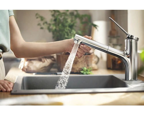 Frau benutzt einen Wasserhahn aus Metall über einem Spülbecken in der Küche