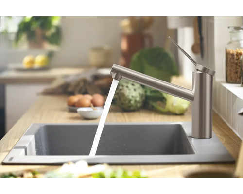 Küchenspüle mit Wasserhahn und laufendem Wasser in einer hellen Küche.