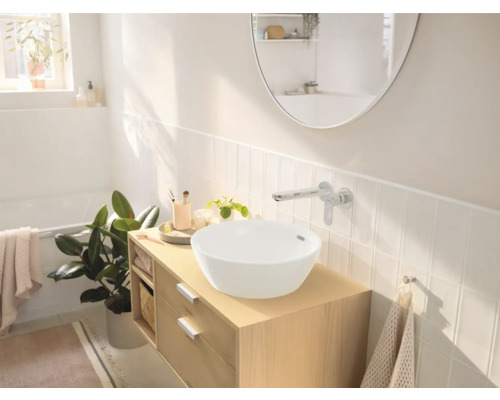 Helles Badezimmer mit Aufsatzwaschbecken, Waschtisch und Wandarmatur vor weißem Fliesenspiegel