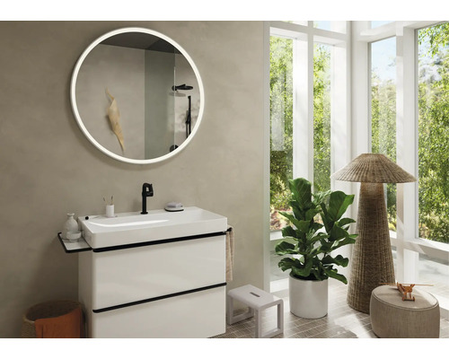 Badezimmer mit Waschtisch, rundem Spiegel mit Beleuchtung und Zimmerpflanze