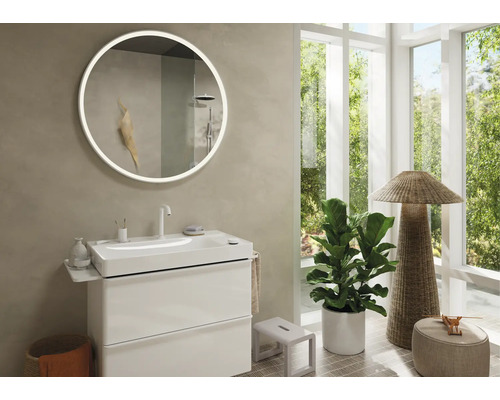 Helles Badezimmer mit rundem Spiegel mit Beleuchtung, Waschbeckenunterschrank und Zimmerpflanze