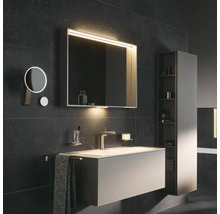 Badezimmer mit Waschtisch, Spiegelschrank mit Beleuchtung, Kosmetikspiegel und Hochschrank für Badezimmerutensilien.