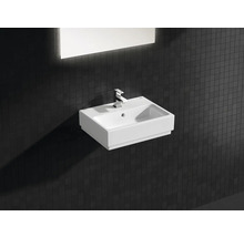 Keramikwaschbecken mit Armatur und rechteckigem Spiegel im Badezimmer.