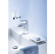 Badezimmerwaschbecken mit Armatur, Seife, Seifenschale, Handtuch, Zahnputzbecher und Zahnbürste.