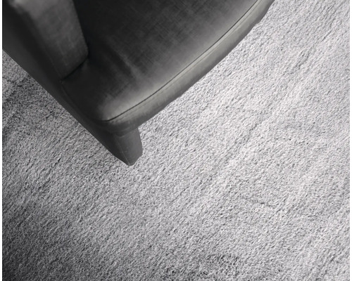 Detailansicht eines hellen Teppichs neben einem Möbelstück