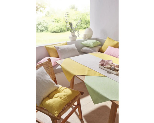 Tischdekoration mit Tischläufer, Kissen und Stuhl mit Kissen in einem hellen Raum