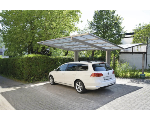 Ein weißes Auto steht unter einem Carport auf einem gepflasterten Parkplatz.