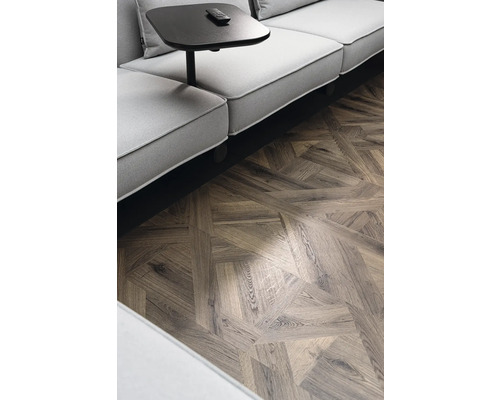 Detailaufnahme eines Raumes mit einem Sofa, einem Beistelltisch und einem Parkettboden im Fischgrätmuster.