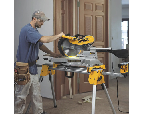 Ein Mann bedient eine DeWalt Kappsäge auf einem Arbeitstisch in einem Raum.