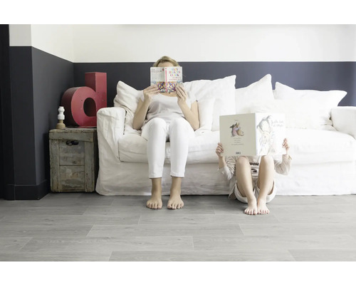 Wohnzimmer mit weißem Sofa, Holzkiste und Personen, die Bücher lesen