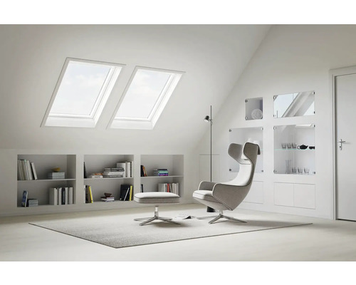 Helles Dachzimmer mit Dachfenstern, Regalen und Sessel