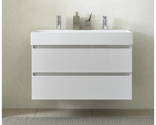 Weißer Waschtisch mit zwei Schubladen, Armaturen, Seifenspender und Zahnputzbecher im Badezimmer.