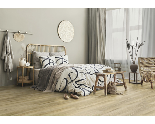 Helles Schlafzimmer mit Bett, Nachttisch und Rattansessel