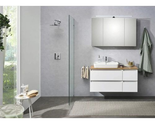 Helles Badezimmer mit Waschbeckenunterschrank, Spiegelschrank, Dusche und Badematte.