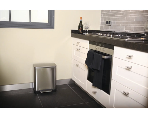 Moderne Küche mit Edelstahl-Treteimer, weißen Schränken und dunkler Arbeitsplatte