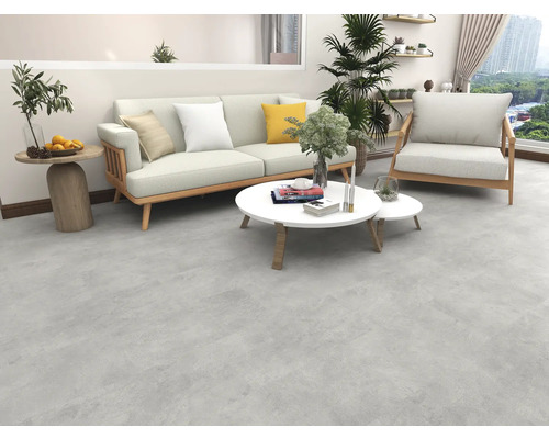 Wohnzimmer mit Sofa, Sessel und Couchtischen auf grauem Boden.