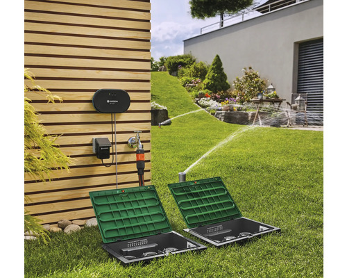 Gardena Bewässerungssystem im Garten mit Rasensprengern und Steuerungsanlage an der Hauswand