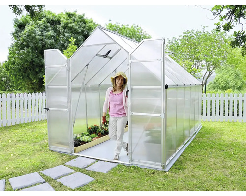 Gewächshaus im Garten mit offener Tür und einer Frau, die es betritt