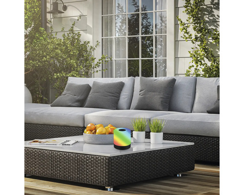 Terrassenszene mit Sofa, Couchtisch, Obstschale, Topfpflanzen und einer Tischleuchte mit Farbwechsel.