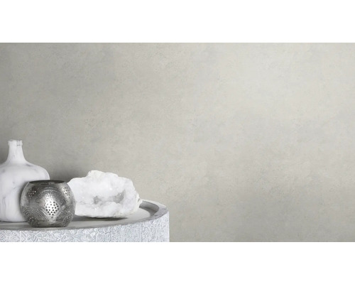 Dekorative Szene mit Vase, Teelichthalter und Schmuckstein auf einem Tisch vor einer hellen Wand