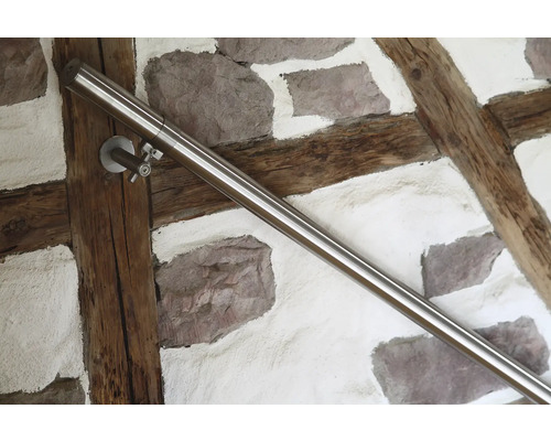 Edelstahl Handlauf an einer Wand mit Steinen und Holzbalken