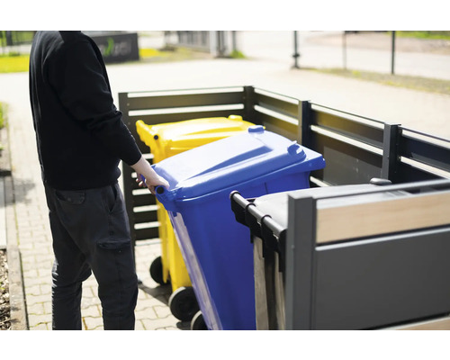 Person schiebt blaue Mülltonne in Mülltonnenbox
