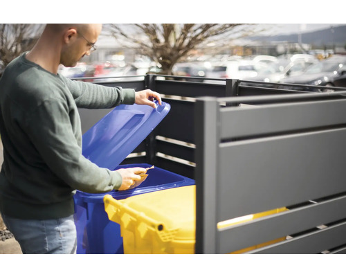 Mann öffnet Mülltonnenbox mit zwei Mülltonnen